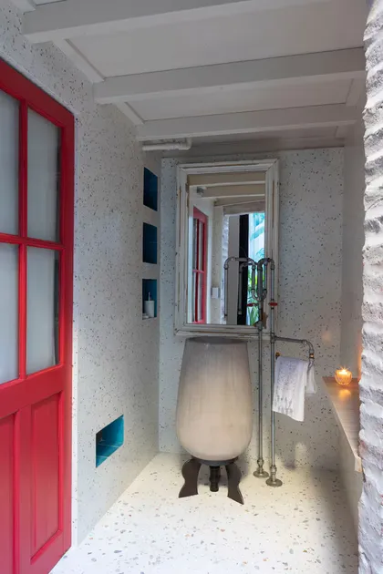 Baño moderno con puerta roja y lavabo de pedestal texturizado — proyecto Casa Arcos, por Silvia Soqueff, en Núñez