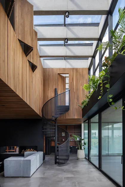 Pasillo con doble altura, escalera espiral y techo vidriado luminoso — proyecto CASA CONSERVATORIO, por GMARQ, en Belén de Escobar