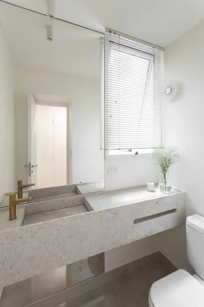 Baño moderno minimalista con lavabo doble de piedra y grifería dorada — proyecto Libertador, por Bouré Studio, en Palermo