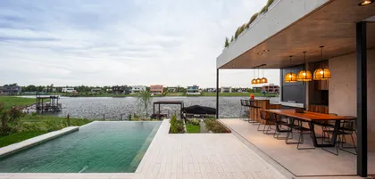 Piscina infinita y comedor exterior moderno frente al lago — proyecto Casa Boating, por LSA. , en Belén de Escobar
