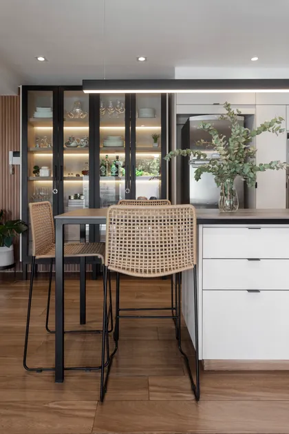 Cocina moderna con isla de rattan y vitrinas iluminadas — proyecto Casa en Martinez, por JT ARQUITECTURA, en Martínez
