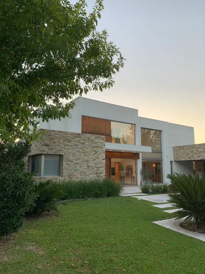 Fachada moderna con piedra y vidrio — proyecto CASA LR 56 - SOFITEL LOS CARDALES  , por Carolina Depetris, en Los Cardales