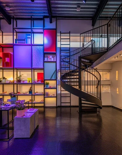 Escalera caracol en doble altura con iluminación LED azul y rosa — proyecto Showroom Melissa, por Pricila Dalzochio