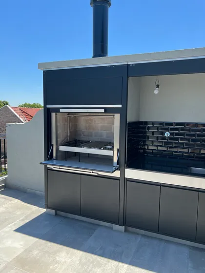 quincho moderno con parrilla y gabinetes negros — proyecto DEPTO MARTINEZ, por Estudio Grupo 32, en Martínez