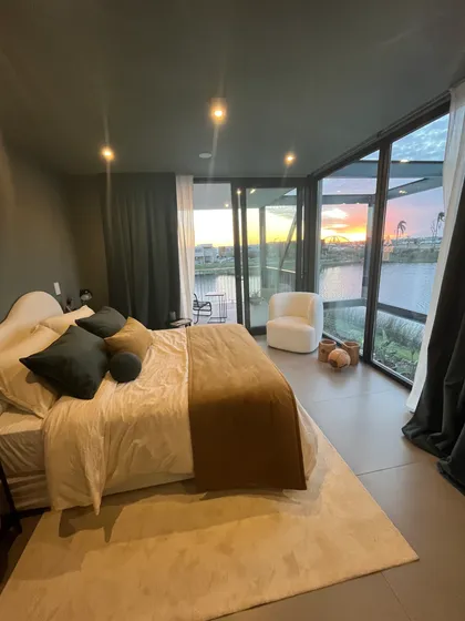 dormitorio moderno con vistas al mar y ventana de piso a techo — proyecto Le chambre verte, por BRand arquitectura / BRand homes, en Belén de Escobar