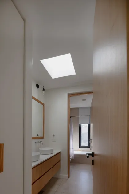 Baño moderno con tragaluz y vanitory de madera — proyecto CASA RuZa, por Alfredo Orfila arquitectura, en Benavidez