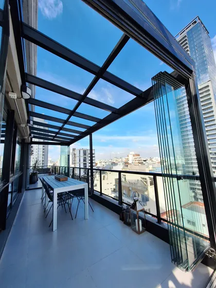 balcón moderno con cerramiento de vidrio y vista urbana — proyecto TOLDER - TECHOS DE VIDRIO, por Argentina en Obra 2024, en Rincón de Milberg