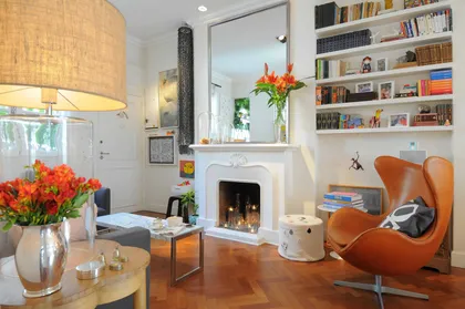 living moderno con chimenea, sillón naranja y biblioteca flotante — proyecto Santa Fe, por Estudio Diez Muzzio, en CABA