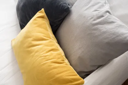 Tres almohadones de colores sobre una cama blanca — proyecto Proyecto Posadas, por URBANO estudio, en Recoleta