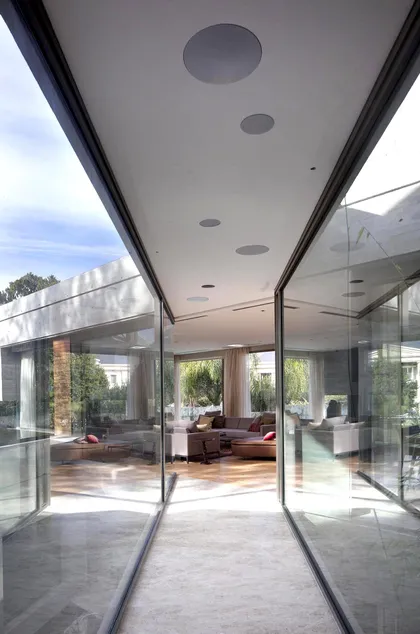 Sala de estar moderna con pasillo de vidrio y mucha luz natural — proyecto Acasusso, por Remy Arquitectos, en Acassuso