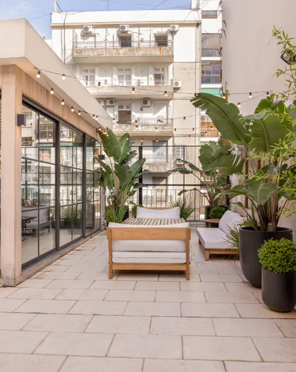 Terraza moderna con muebles de madera y plantas exuberantes en entorno urbano — proyecto Terraza en la ciudad, por Casa Cunia, en CABA