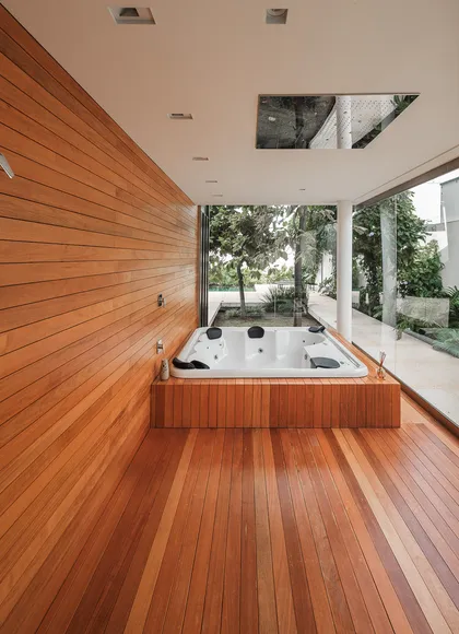 Baño moderno con jacuzzi, pared de madera y ventanales al exterior — proyecto Casa RV, por Daniel Santo