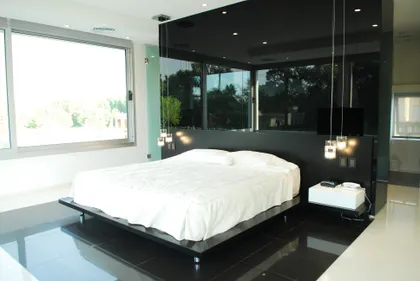 dormitorio moderno minimalista con grandes ventanales y superficies negras brillantes — proyecto Pilar House , por Vanguarda Arquitectos, en Pilar