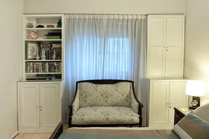 Dormitorio luminoso con sillón tapizado frente a ventanal y guardarropas blancos — proyecto Marcelo T de Alvear, por Rioja Arquitectura, en Recoleta