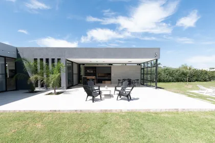 Patio moderno de hormigón con muebles de rattan y grandes ventanales — proyecto VIVIENDA D.A, por Lorenabusquetsarquitectura, en Córdoba