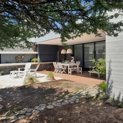 Comedor exterior moderno bajo pérgola con vegetación exuberante — proyecto VIVIENDA M.A, por Lorenabusquetsarquitectura, en Córdoba