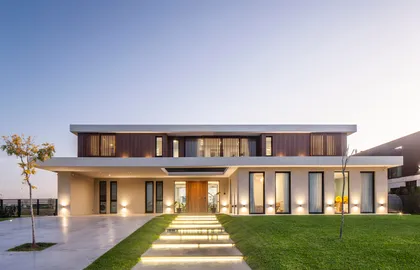 Fachada moderna de dos pisos con grandes ventanales y detalles en madera — proyecto CASA C313, por A'PRIMA - Arquitectura Sustentable, en Provincia de Buenos Aires