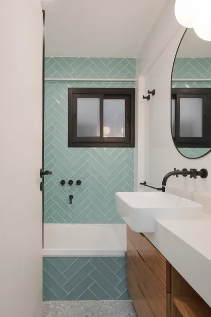 Baño moderno con pared de azulejos en espiga y vanitory de madera — proyecto Obra Aguirre, por SYA Arquitectas, en Palermo
