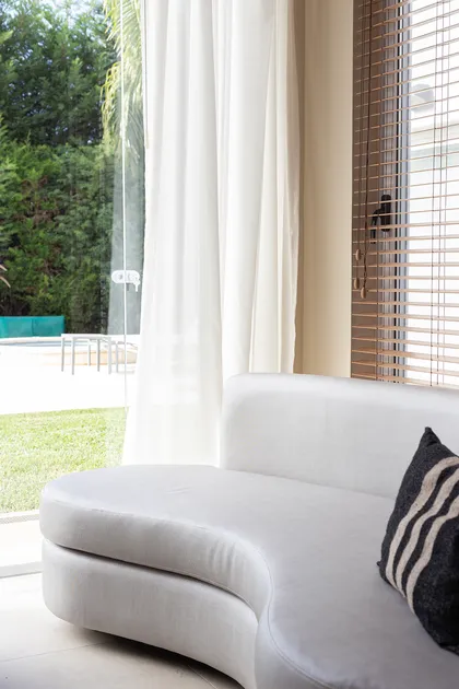 Living moderno con sofá curvo blanco y ventanales amplios — proyecto Casa Canning, por Gaby Alfonso, en Canning