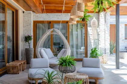 Terraza semi-exterior con techo de madera, ladrillo blanco y mobiliario de ratán — proyecto Projeto Destaque Club&Casa, por OKA ARQUITETURA