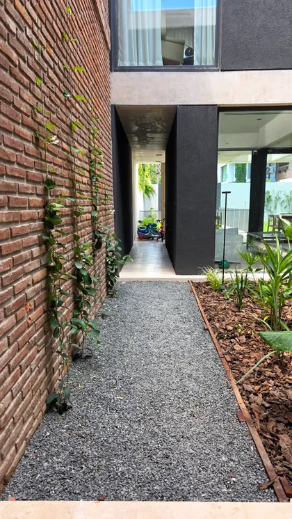 fachada moderna con pared de ladrillo y camino de grava — proyecto Martinez, por Marcela García Brünner Paisajista, en Martínez