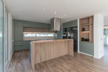 Cocina moderna con isla de madera y gabinetes verdes — proyecto CASA CALA, por Auge desarrollos & crowdfunding, en Nordelta