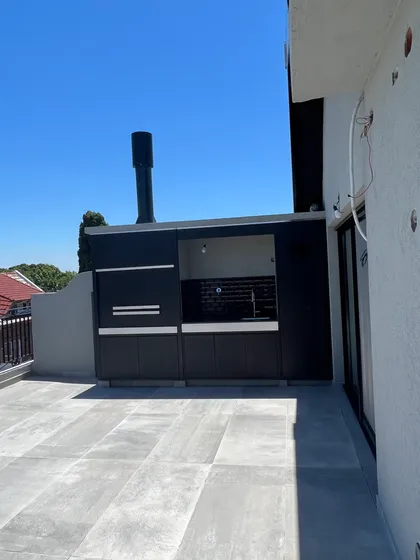 Cocina exterior moderna con parrilla y patio de baldosas grises — proyecto DEPTO MARTINEZ, por Estudio Grupo 32, en Martínez