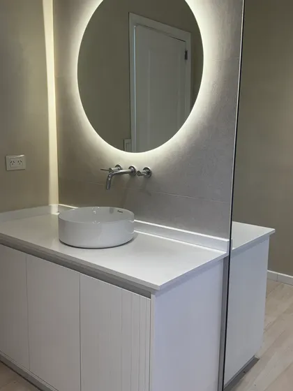 Baño moderno con espejo redondo retroiluminado y vanitory flotante — proyecto CASA LA LOMADA , por Estudio Grupo 32, en Pilar