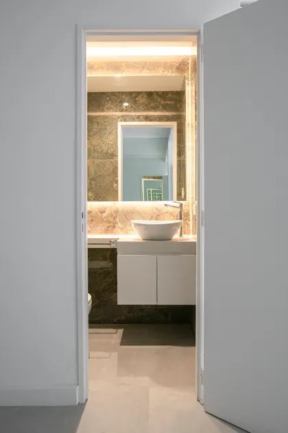 Baño moderno con revestimiento de mármol y luz indirecta — proyecto Obra Martinez A, por Arq. Lourdes Yarade Saravia, en Martínez