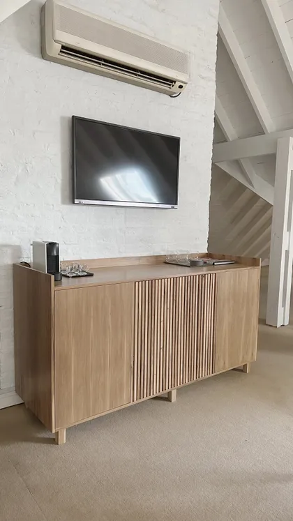 Sala con credenza de madera y techo a dos aguas — proyecto Proyecto Roca, por Alejandra Nusenovich, en Béccar