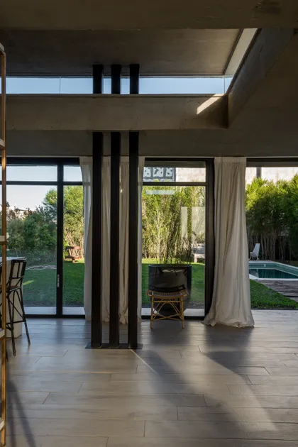 Living moderno con concreto y vista al jardín — proyecto CASA JOTA, por arquitectura.JD, en La Plata