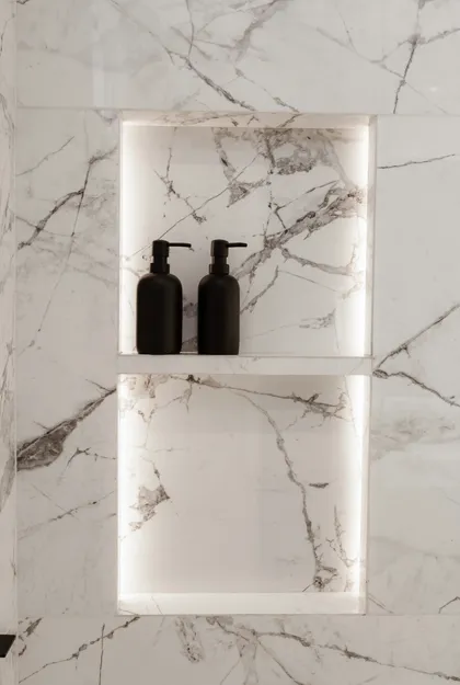 Baño moderno con nichos iluminados y dispensadores negros — proyecto Alvear | Redefining luxury, por Ren Studio, en Recoleta