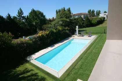 Piscina moderna rectangular rodeada de deck de piedra y vegetación — proyecto  Inmuebles, por Geo Estudio, en Buenos Aires