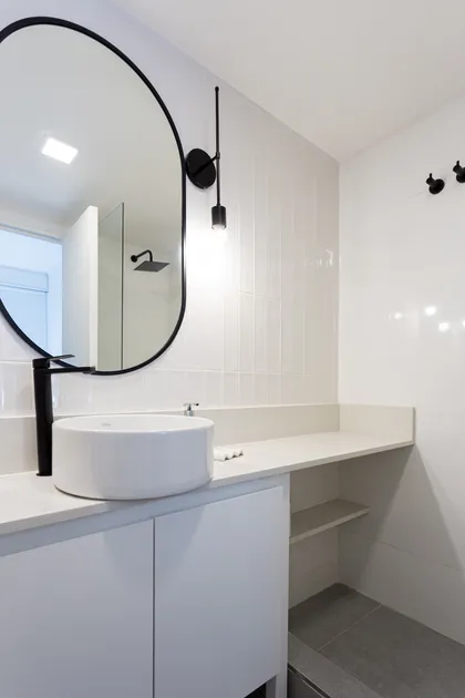 Baño moderno con espejo ovalado, bacha redonda y grifería negra — proyecto Obra Clay, por SYA Arquitectas, en Palermo