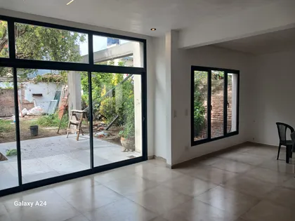 Sala de estar moderna conectada a patio exterior con grandes ventanales — proyecto Casa zABALA, por Sep Arquitectura , en La Plata