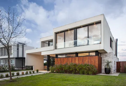 Fachada moderna con concreto blanco y madera natural — proyecto Casa BJM, por Vanguarda Arquitectos, en Belén de Escobar