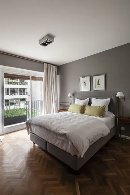 Dormitorio gris contemporáneo con cama tapizada y ventanal a terraza — proyecto GO2219, por Facundo Arana Arquitecto