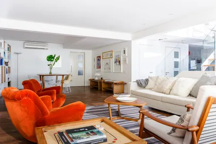 Living moderno con sillones naranja vibrantes y mucha luz — proyecto Piso en Libertador III, por Gutman+Lehrer Arquitectas, en CABA