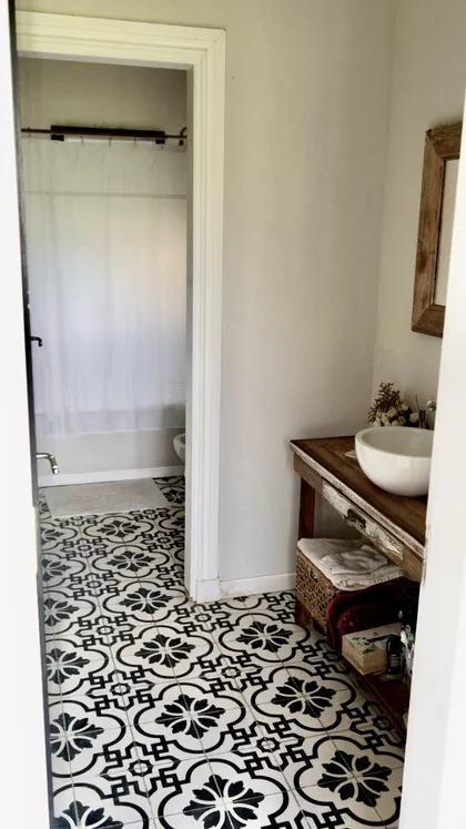 Baño con piso de patrón geométrico y vanitory de madera rústica — proyecto Los Jazmines Pilar del Este, por Marconi Silva Arquitectos, en Pilar del Este