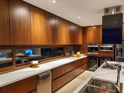 Cocina moderna con gabinetes de madera integrados y mesadas de mármol blanco — proyecto EL GOLF, NORDELTA , por Greschek Obras , en Nordelta