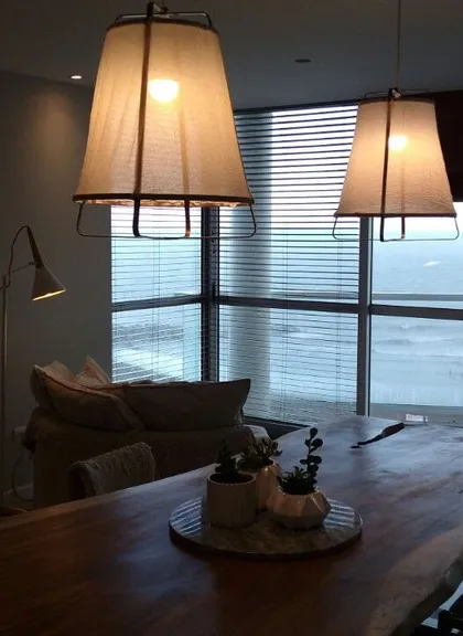 Living comedor moderno con mesa de madera y vista al mar — proyecto Departamento MH, por Vicky Hurrell, en Mar del Plata