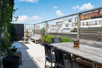 Terraza con deck de madera y plantas, vista urbana — proyecto Quintana, por Escalante Vela Arquitectos, en CABA