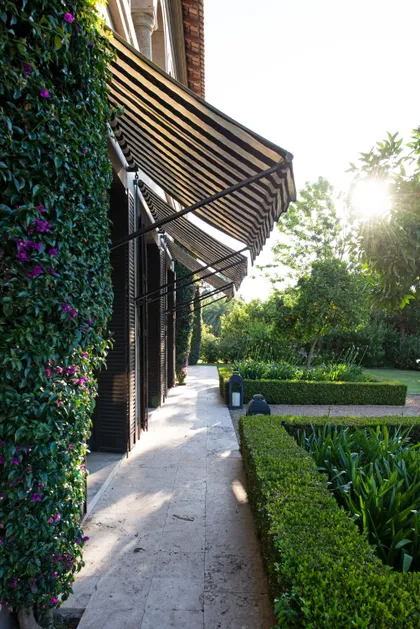 Terraza con pergola negra, plantas trepadoras moradas y vista al jardin — proyecto Casa Toscana , por Estudio Du 
