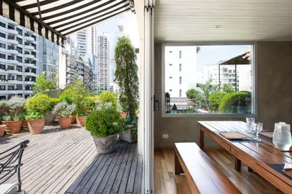 Terraza con deck de madera, plantas en macetas y vista a la ciudad — proyecto Estudio Cerviño, por Estudio Du , en Palermo
