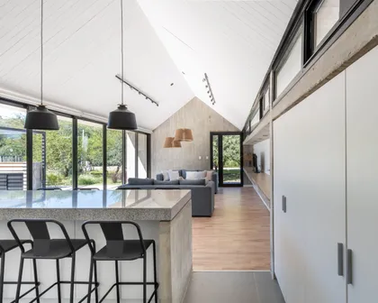 Cocina moderna con isla, doble altura y amplios ventanales hacia jardín — proyecto Casa TT, por Grupo Studio, en Villa Allende