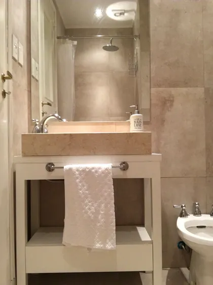 Bano moderno con mesada marmol, espejo grande y ducha vidrio — proyecto Salguero, por Rioja Arquitectura, en Palermo