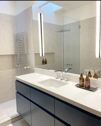 Baño moderno con vanitory azul oscuro, encimera de piedra y ducha de vidrio — proyecto Baños Belgrano, por Cudini Estudio, en Belgrano