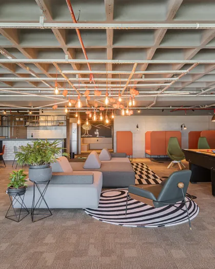 Oficina abierta con techo de madera, sillones grises y anaranjados — proyecto Projeto 2, por Studiok