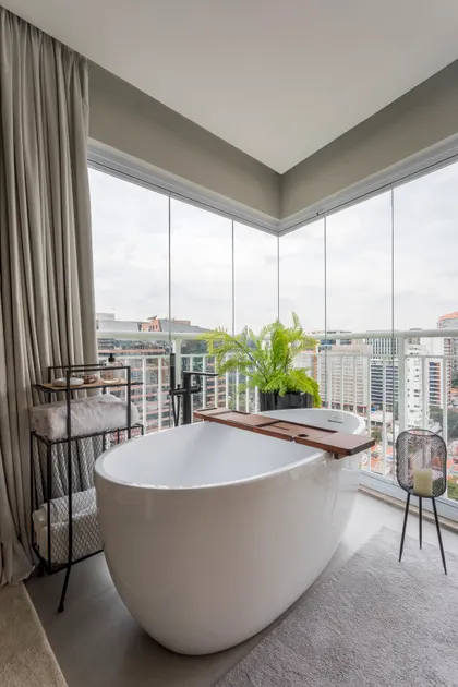 Baño moderno con bañera exenta en balcón vidriado y vistas urbanas — proyecto Brunno-Fernanda, por Mariana Coser