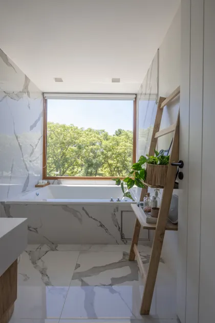 Baño moderno con ventana grande, bañera exenta y paredes de mármol_like — proyecto CASA BaCa, por Alfredo Orfila arquitectura, en Benavidez